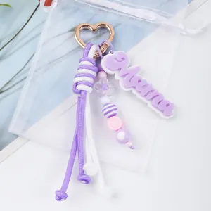 Detailed macro view of a purple woven rope keychain featuring Mama charm and heart beads