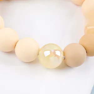 Close-up macro view of silicone and acrylic beads on a candy-colored wristlet