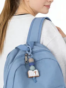 Christlicher Silikon-Perlen-Schlüsselanhänger mit Bibel-Charm an blauem Rucksack-Reißverschluss.