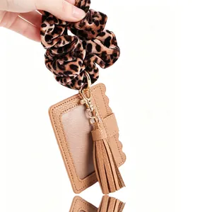Detailansicht eines Leoparden-Scrunchies mit braunem PU-Leder-Kartenhalter und Quasten-Anhänger