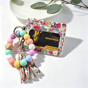 Détail du porte-cartes à imprimé floral avec bracelet en perles de silicone et gland