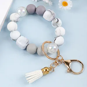 Detail view of marble pattern silicone beaded wristlet keychain with white tassel and gold clasp
