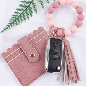 Detail view of pink leather card holder with silicone bead wristlet and fringe tassel