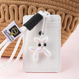 Detailed view of a white leather card holder with an iridescent balloon dog charm accessory