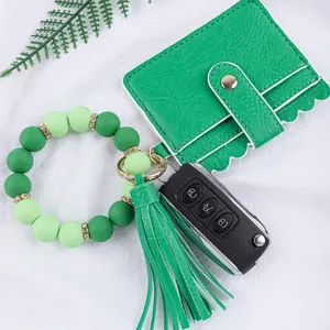 Detail of green silicone bead bracelet with matching leather card wallet and tassel