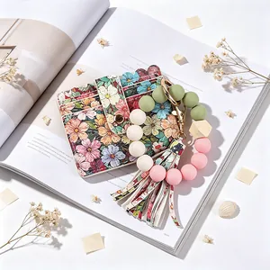 Gros plan d'un porte-cartes fleuri avec un porte-clés à pompon en perles de silicone