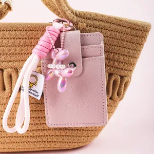 Close-up of pink card holder with braided rope strap and pearl balloon dog charm