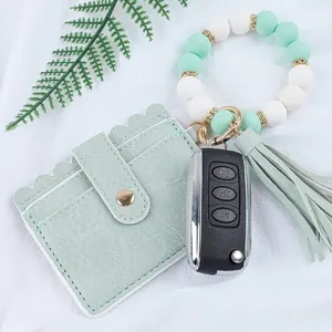 Detail view of mint green silicone beaded wristlet with leather card holder and tassel