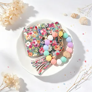 Détail du porte-cartes floral avec bracelet en perles de silicone colorées et pompon