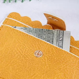 Detail shot of a yellow scalloped edge leather card holder with gold snap button