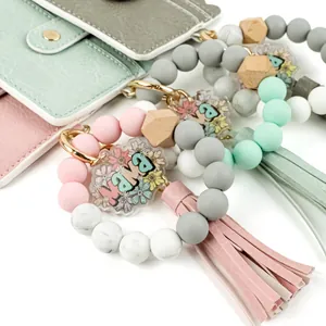 Gros plan d'un bracelet en perles de silicone avec breloque MAMA et gland en cuir