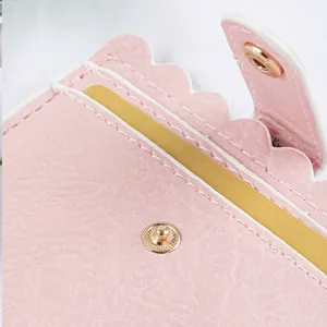 Close-up detail of a pink leather card holder with scalloped edges and gold snap
