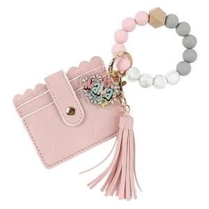 Vue détaillée d'un porte-cartes en cuir PU rose avec perles en silicone et pompon