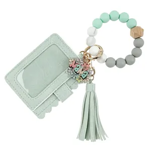 Détail du porte-carte en simili cuir vert menthe avec breloque florale mama et pompon