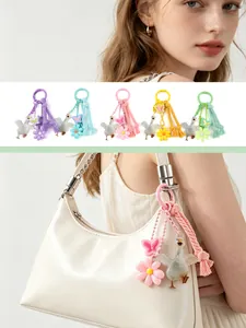 Detailed view of colorful goose and flower bag charms displayed on a white handbag.