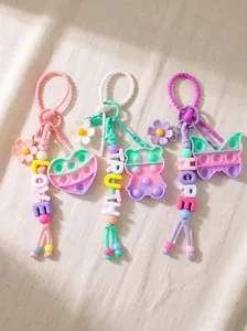 Detail view of colorful beaded bag charms featuring Pop-it fidget toys and flower designs