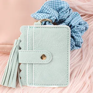 Close-up of mint green PU leather card holder featuring tassel and scalloped edge detail