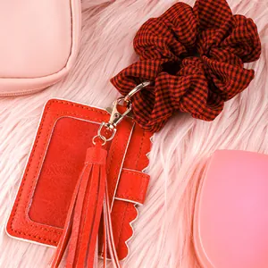 Detail view of a red PU leather card holder with tassel and checkered scrunchie keychain set.