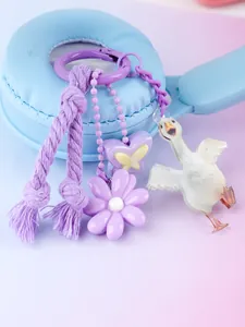 Close-up of purple keychain with flower, butterfly, and goose charms on headphones
