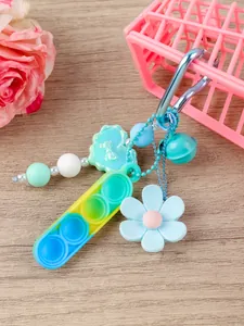 Detalle de llavero pop fidget de silicona con flor azul y amuleto de campana