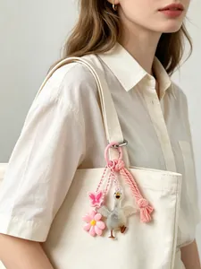 Detail of a cute goose keychain with pink flower and butterfly charms on a canvas bag.