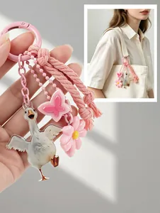 Detailed view of a pink goose keychain with flower charms hanging on a white tote bag