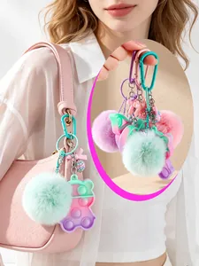 Detail view of colorful pom-pom bear fidget toy keychain attached to a pink handbag