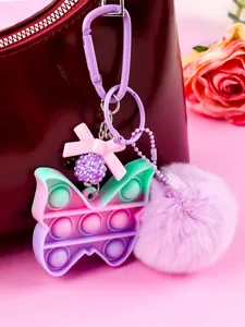 Detail view of colorful butterfly pop-it keychain with purple fluffy pom-pom charm