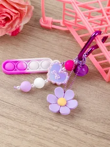 Detalle de llavero pop it rosa y morado con colgantes de flores y corazones de silicona suave