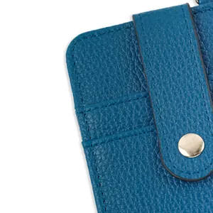 Close-up detail of blue litchi grain leather card holder featuring a gold snap button.