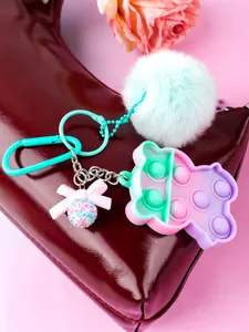 Detail of mint green pompom and bear-shaped silicone pop-it fidget toy bag charm.