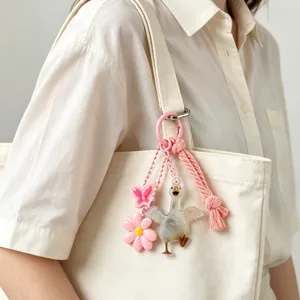 Cute acrylic goose and pink flower bag charm hanging on a stylish beige canvas tote bag