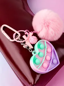 Detailed view of a heart-shaped pop fidget toy keychain featuring a pink fluffy pompom