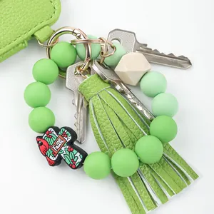 Green leather card holder keychain with beaded bracelet, tassel, and faith charm