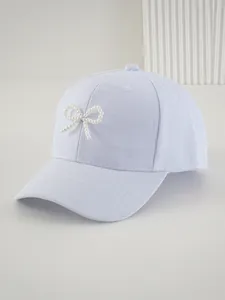 Dettaglio ravvicinato del cappellino azzurro con fiocco decorativo di perle bianche.