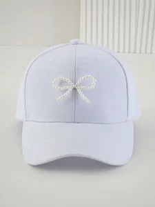 Primo piano di un berretto da baseball azzurro da donna con un elegante fiocco di perle