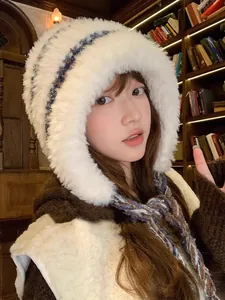 Detail of a cozy white plush ear protection hat with knitted blue-white straps.