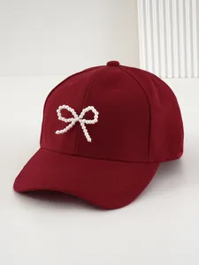 Dettaglio di un cappello da baseball rosso con elegante decorazione a fiocco di perle.