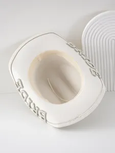 Dettaglio di un cappello da cowboy bianco da sposa con lettere BRIDE in perle eleganti.