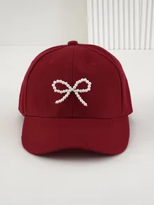 Dettaglio cappellino bordeaux con elegante decorazione a fiocco in perle bianche