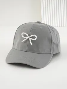Dettaglio cappellino da baseball grigio con elegante fiocco di perline bianche