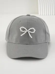 Dettaglio di un berretto da baseball grigio con un'elegante decorazione a fiocco di perle