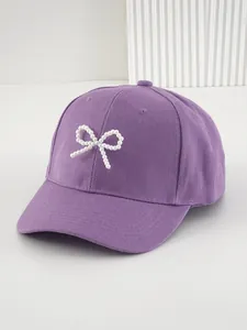 Dettaglio del cappellino da baseball viola con un elegante fiocco decorato di perle