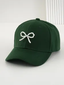 Primo piano di un berretto da baseball verde bosco con un elegante fiocco di perle