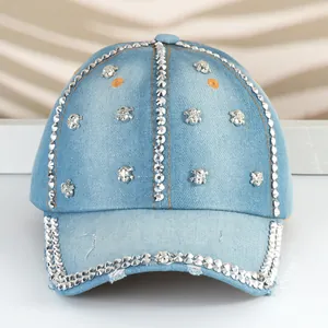Dettaglio di un cappello da baseball in denim con borchie metalliche e piccoli teschi.