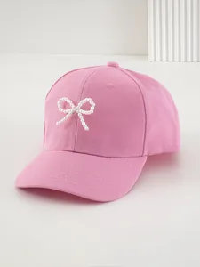 Vista dettagliata di un cappellino rosa con un delicato fiocco di perle bianche sul davanti.