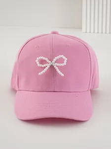 Dettaglio di un berretto da baseball rosa con un elegante fiocco di perle