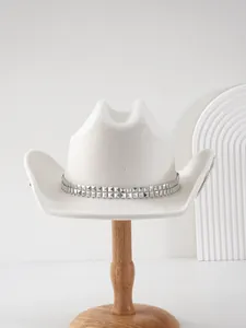 Dettaglio di un elegante cappello da cowboy da sposa bianco con borchie e supporto in legno.