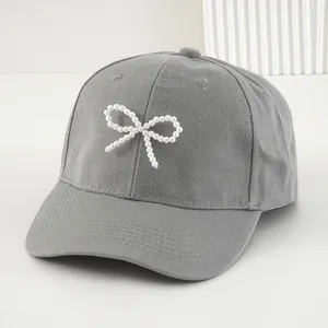 Elegante berretto da baseball grigio da donna decorato con un delicato fiocco di perle bianche.
