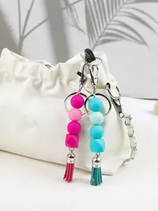 Detailed view of colorful silicone bead keychains with tassels attached to a white handbag